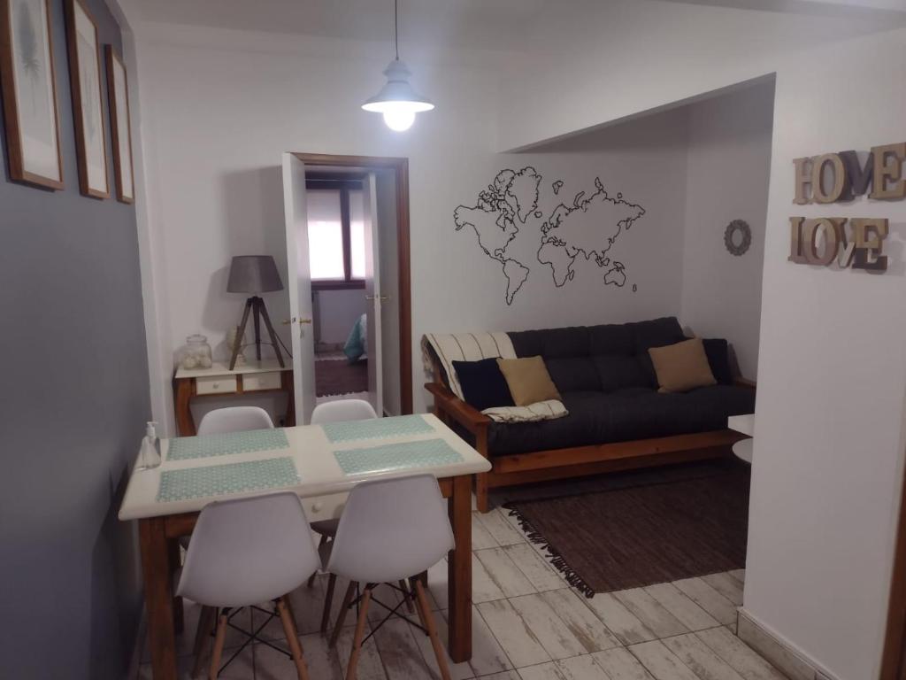 uma sala de estar com um sofá, uma mesa e cadeiras em Departamento vista al mar Playa Las Toscas em Mar del Plata