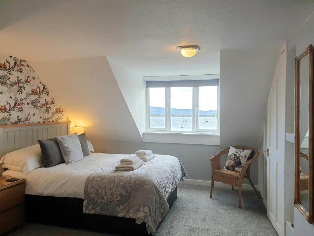 a bedroom with a bed and a window and a chair at Carnaburg Guesthouse in Tobermory