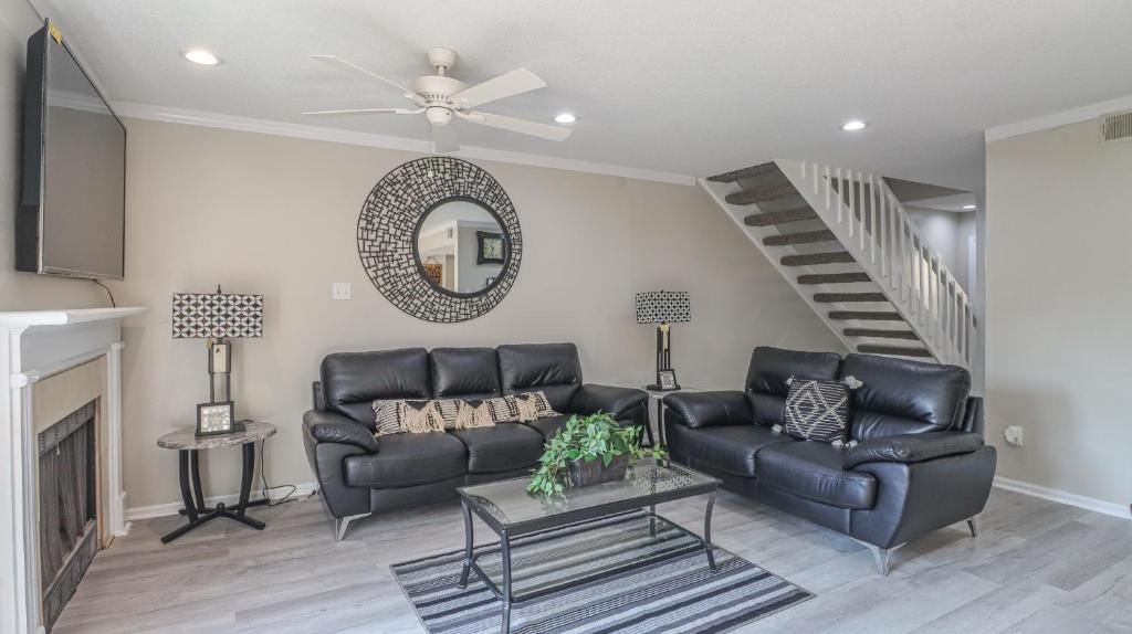 a living room with a black leather couch and a staircase at Spacious Cozy Condo! Perfect for longer stays in Mobile