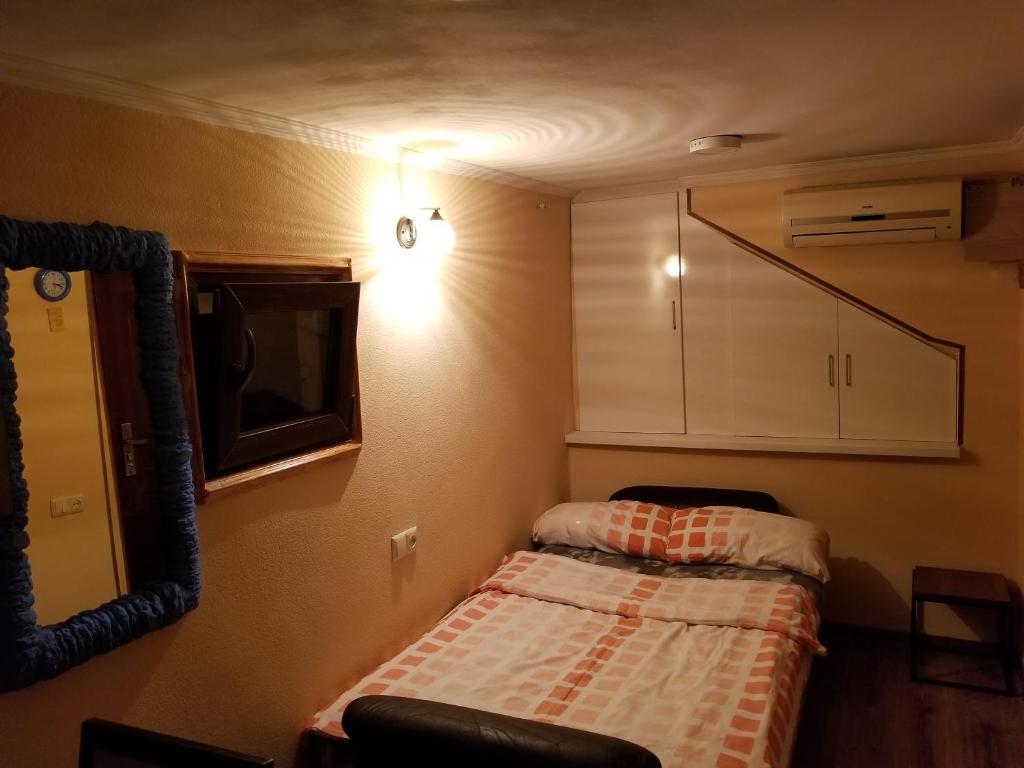 Habitación pequeña con cama y espejo. en Silk House, en Tiflis