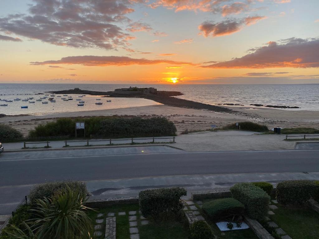 - un coucher de soleil sur une plage avec une route et l'océan dans l'établissement Loriot2 - appartement vue sur mer, à Ploemeur