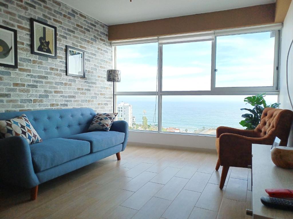 sala de estar con sofá azul y ventana grande en Stylish New Apartment with stunning Ocean View near Miraflores, en Lima