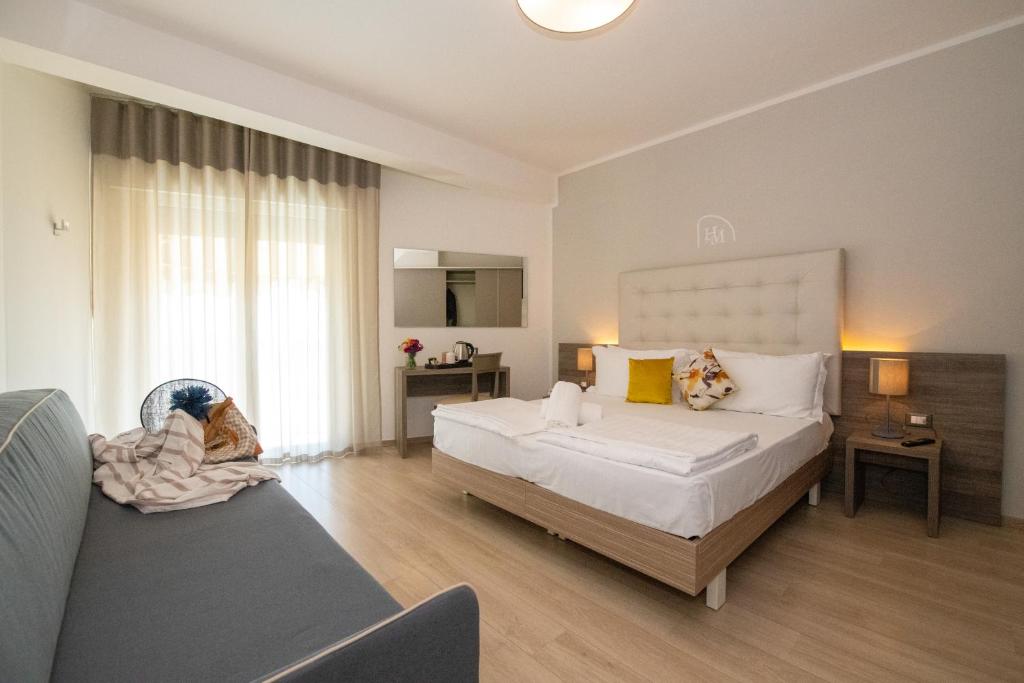 una camera con un grande letto e un divano di Hotel Delle Mimose a Lido di Jesolo