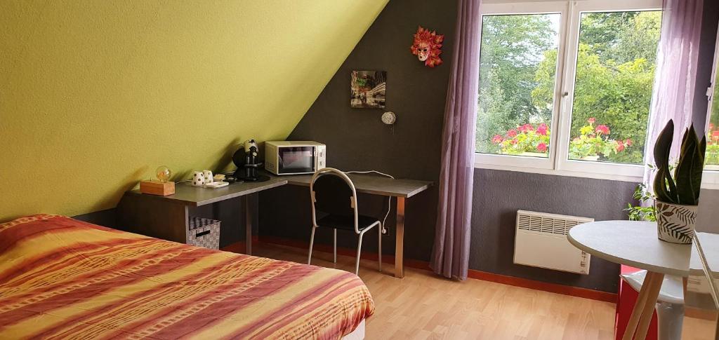 a bedroom with a desk and a bed and a window at Chambre des Acacias 