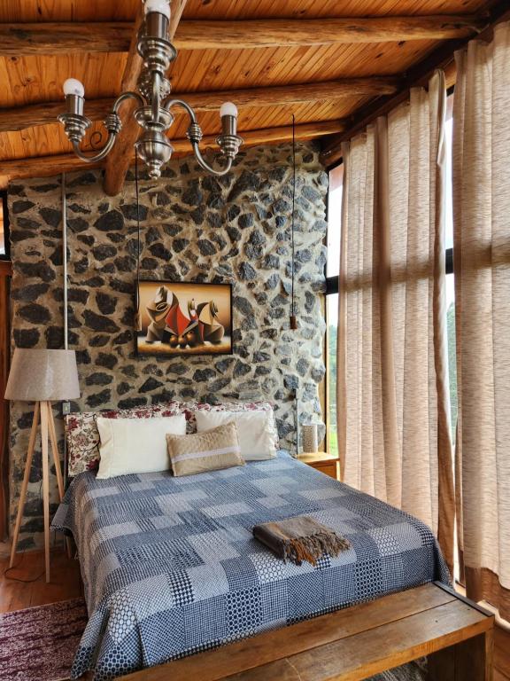 クーニャにあるTiny Houses O Olival - aluguel temporadaのベッドと石の壁のある寝室