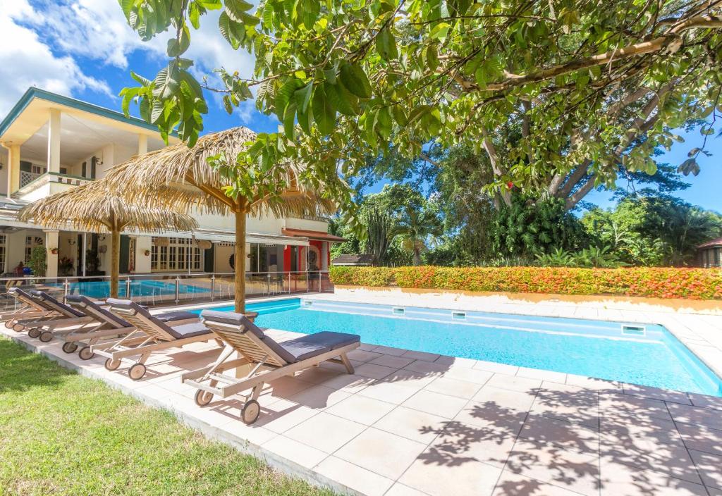 a villa with a swimming pool and two lounge chairs at Habitation du Comté in Sainte-Rose