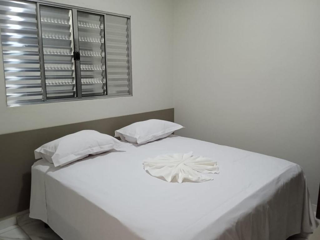 a white bed with two pillows and a window at HOTEL IMPERIO in Aparecida do Taboado