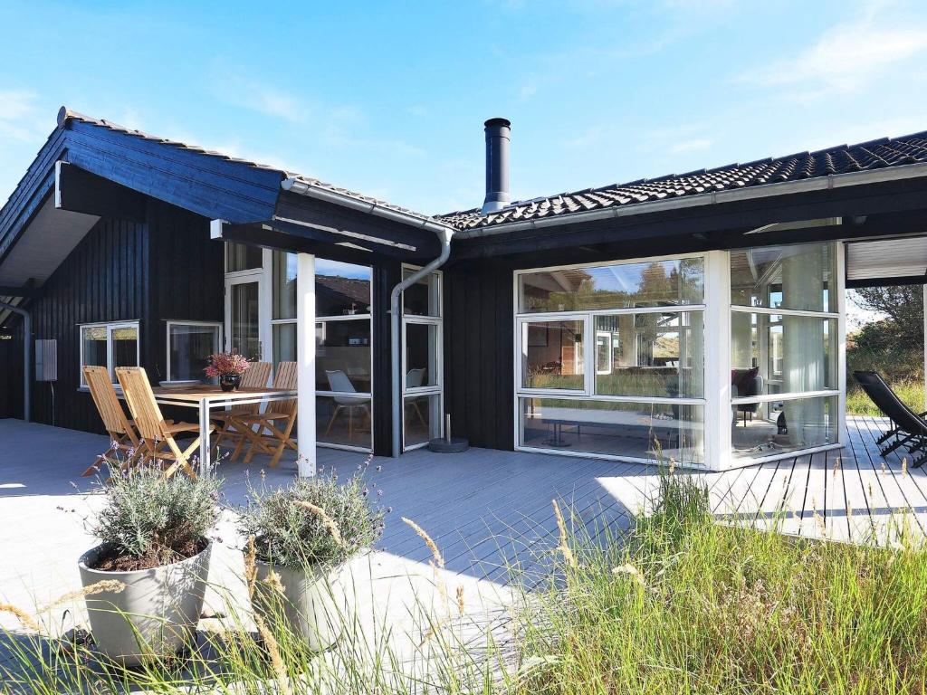ÅlbækにあるThree-Bedroom Holiday home in Ålbæk 56のパティオ(テーブル、椅子付)が備わる家です。