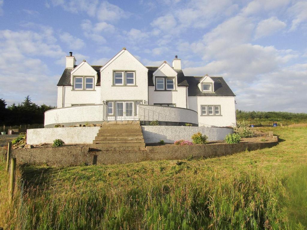 uma grande casa branca sentada no topo de um campo em Knockinaam House em Colfin