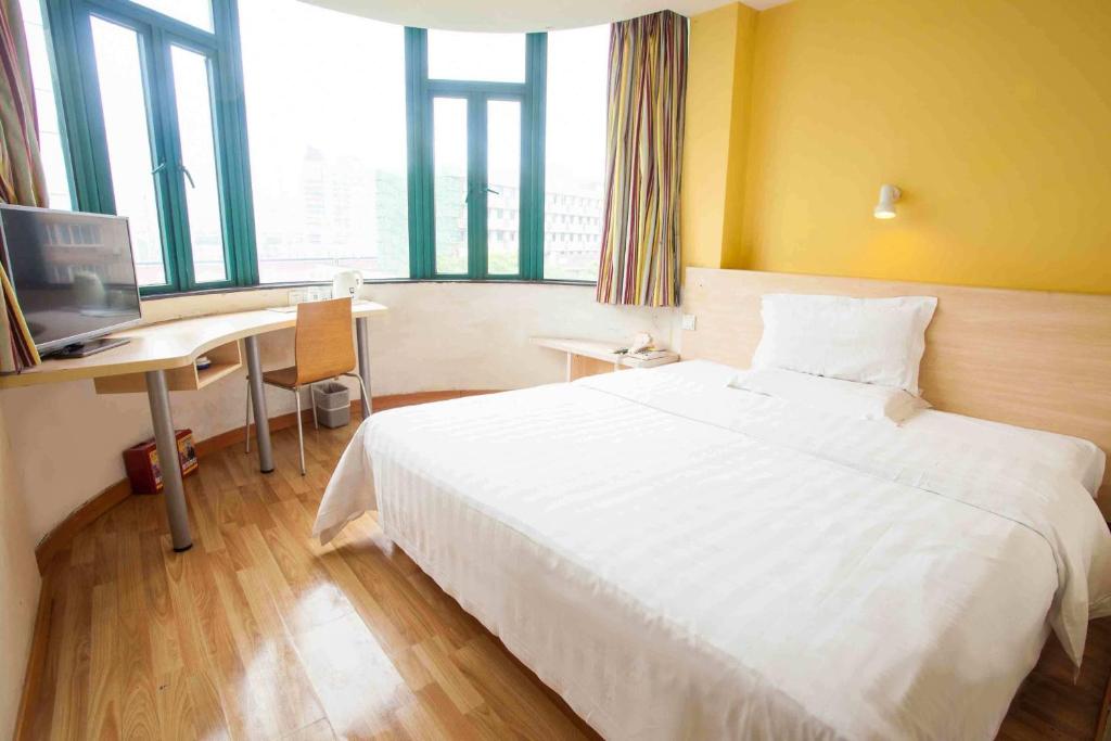 ein Hotelzimmer mit einem weißen Bett und einem Schreibtisch in der Unterkunft 7Days Inn Guangzhou Huanghuagang in Guangzhou