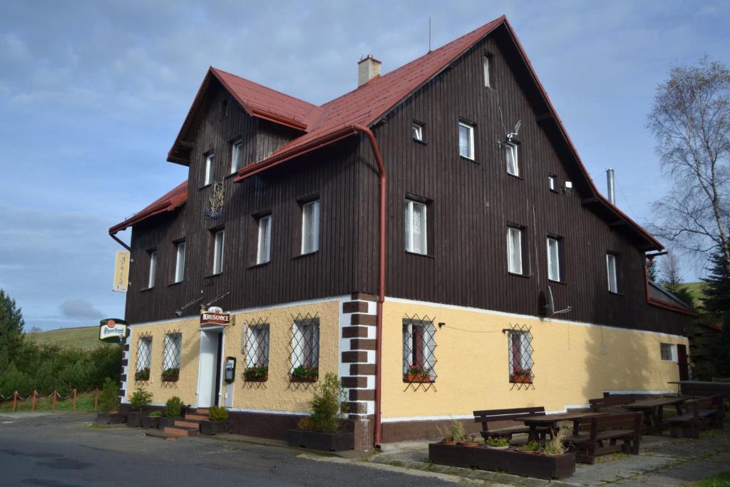 een groot zwart en geel gebouw met een rood dak bij Horský Hotel Arnica in Loučná pod Klínovcem