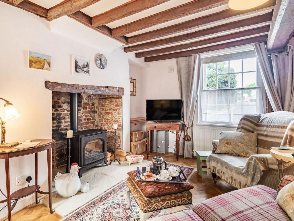 a living room with a fireplace and a tv at Riverside Cottage in Bungay