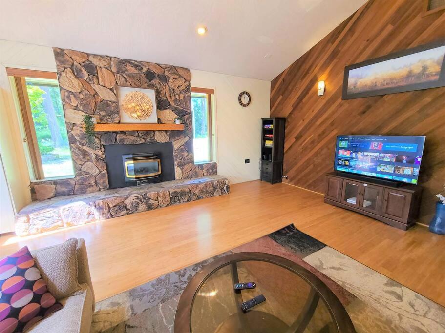 sala de estar con chimenea de piedra y TV en The HideAway en Port Angeles