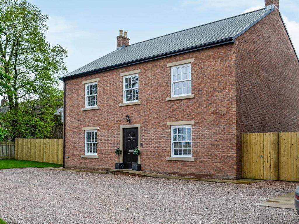 a red brick house with a wooden fence at Chestnuts in Burgh by Sands