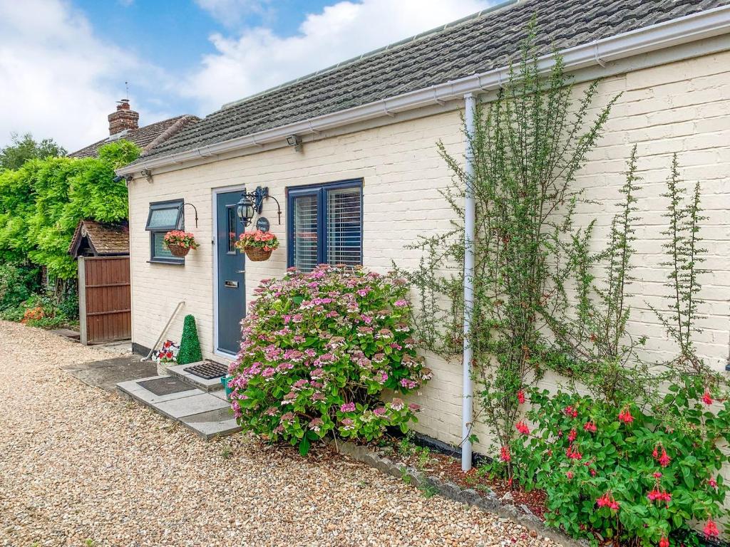 a white house with a blue door and some flowers at Sunbury Cottage in Clanfield