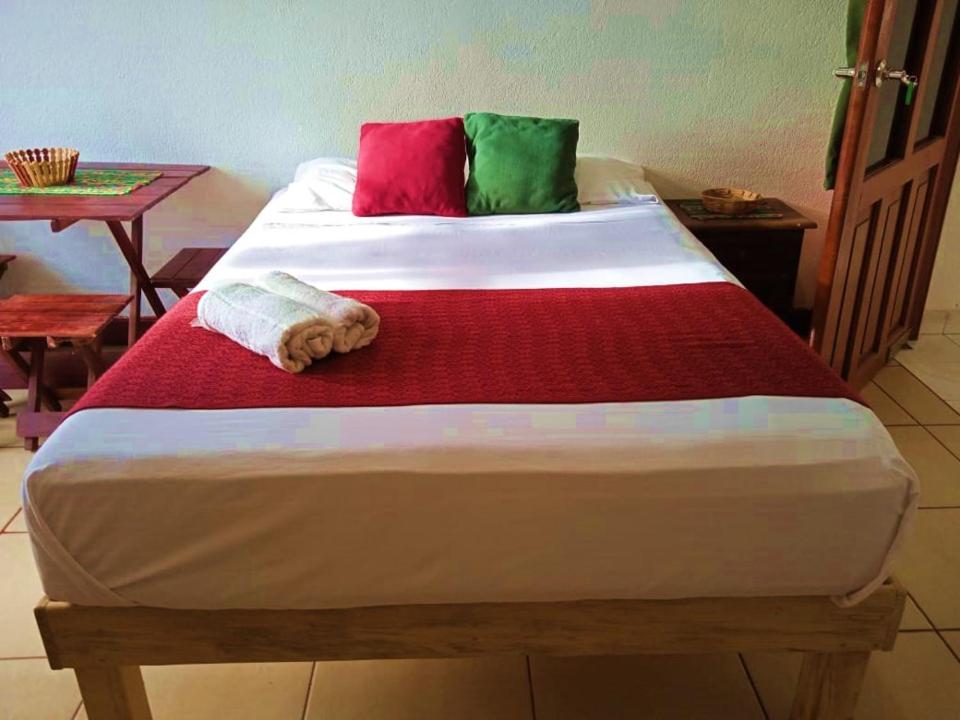 Una cama grande con almohadas rojas y verdes. en Casa Natura en San Cristóbal de Las Casas