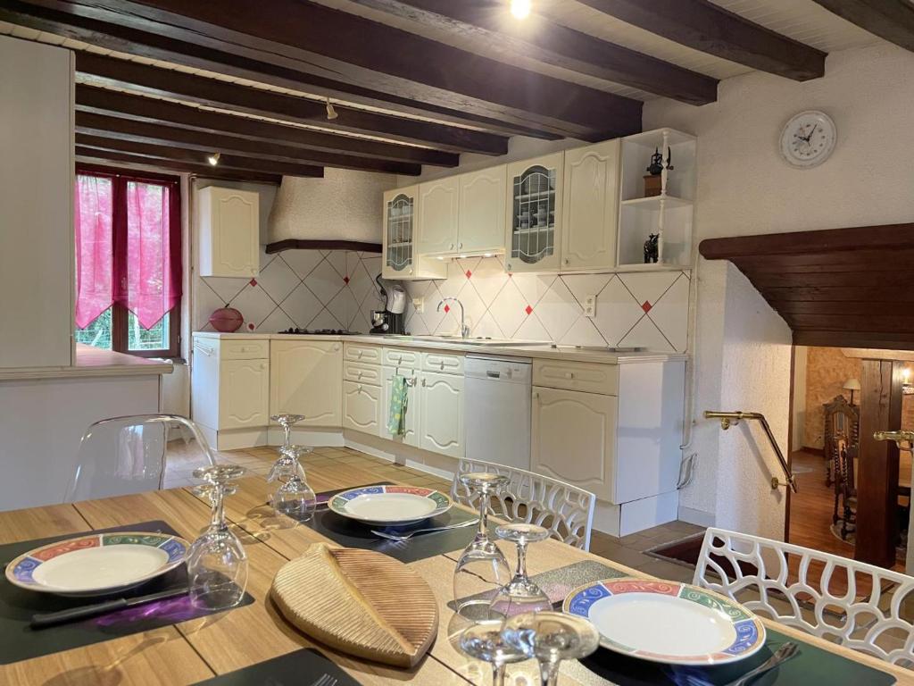 eine Küche mit einem Holztisch mit Tellern und Gläsern darauf in der Unterkunft Gîte Hyds, 4 pièces, 6 personnes - FR-1-489-397 in Hyds