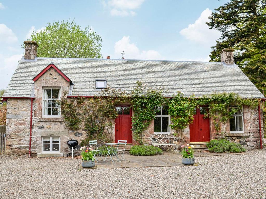 een oud stenen huis met rode deuren en wijnstokken bij Rose Cottage in Blairgowrie