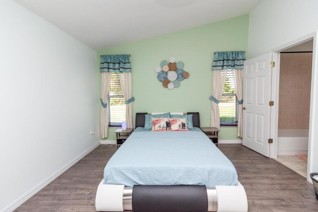 a bedroom with a bed and two windows at Gorgeous Fully Furnished 2-Bedroom Luxury Villa in Kissimmee