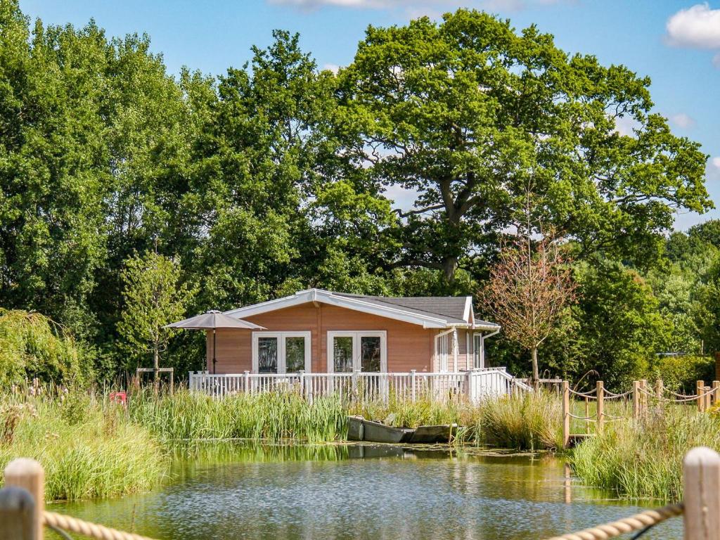 a small pink house next to a pond at Viburnum Lodge in Willington