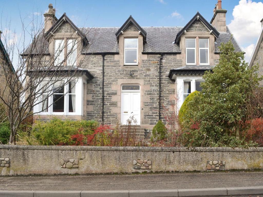 a brick house with a white door on a street at Dallas Brae in Grantown on Spey