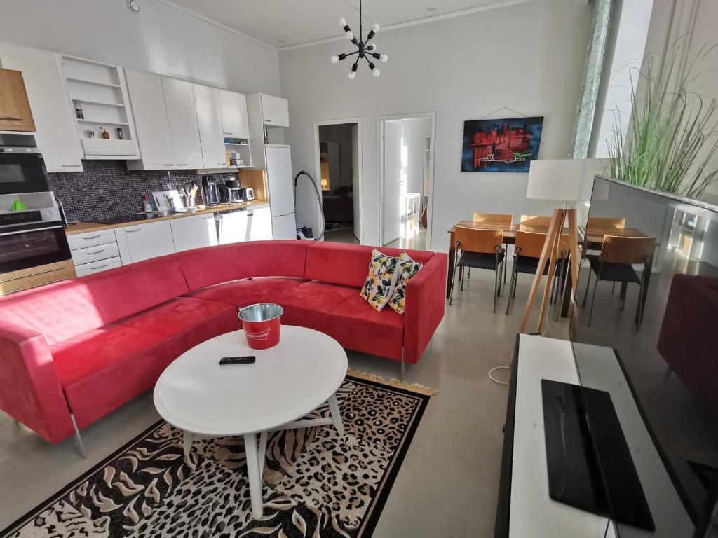 salon z czerwoną kanapą i stołem w obiekcie 2-Bedroom Royal Apartment with Own Sauna in Kotka w mieście Kotka