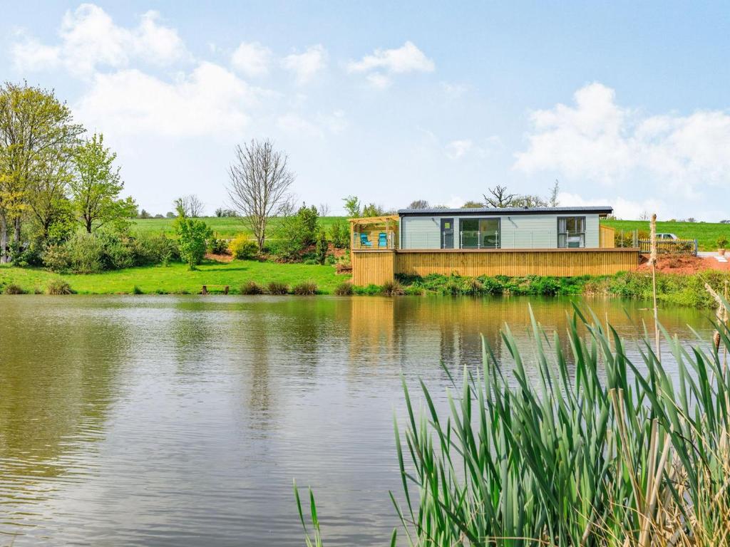 a house on the edge of a lake at Ponsford Ponds - Goosedown Lodge in Cullompton