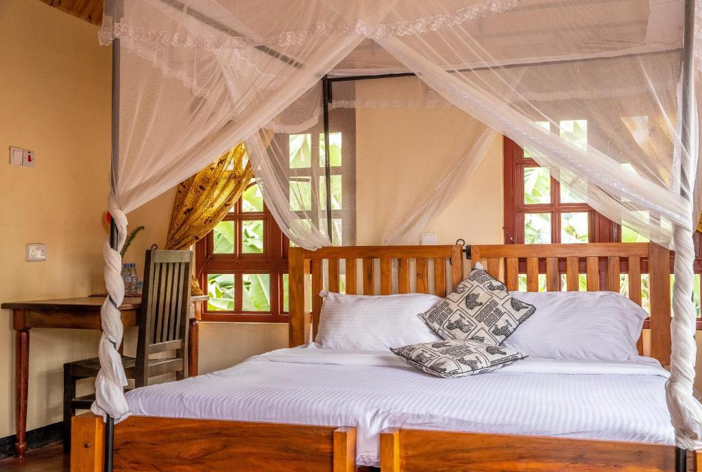 a bedroom with a canopy bed with white sheets and pillows at Christina House in Arusha