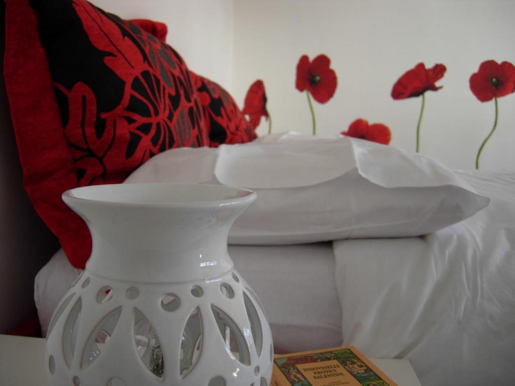 a white vase sitting on a table next to a bed at Secret Garden In The Old Town in Lecce