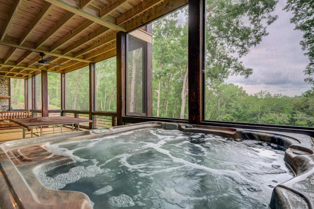 uma banheira de hidromassagem num quarto com janelas em Grizzly Cabin em McCaysville