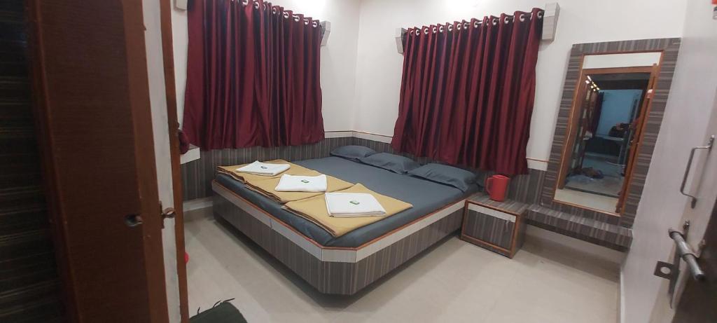 a small bedroom with a bed and a mirror at Sai Raghunandan Guest House in Shirdi