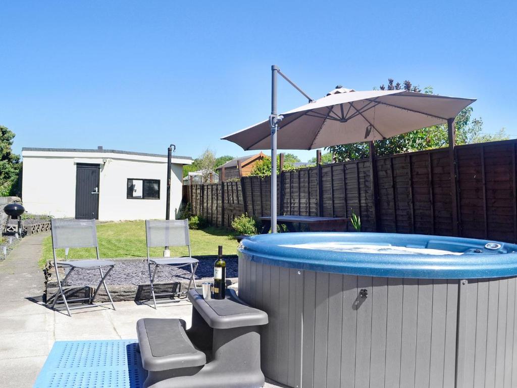 a hot tub with an umbrella and a table and chairs at Ty Bryn Cottage in Kenfig Hill