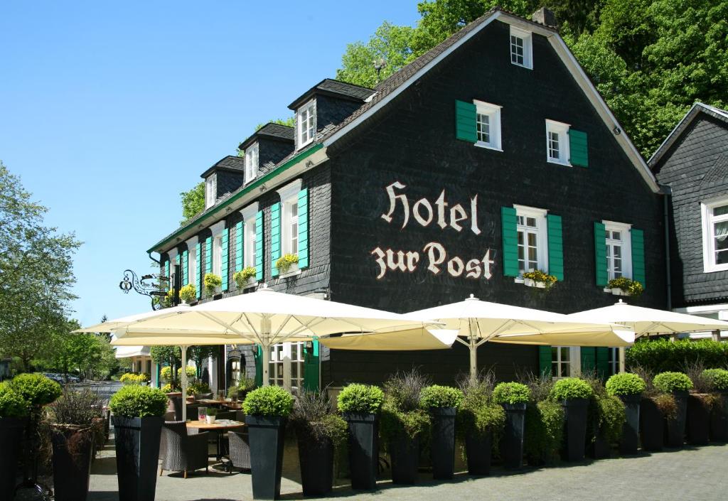 a black building with umbrellas in front of it at Hotel Restaurant Zur Post in Odenthal