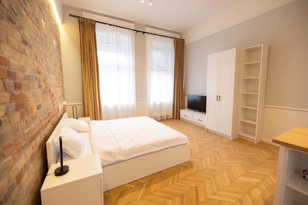 a bedroom with a white bed and a brick wall at Carol Residence in Timişoara