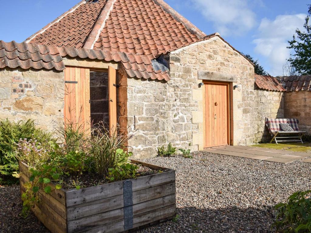 a stone house with a wooden door in a yard at The Roondie in Ladybank