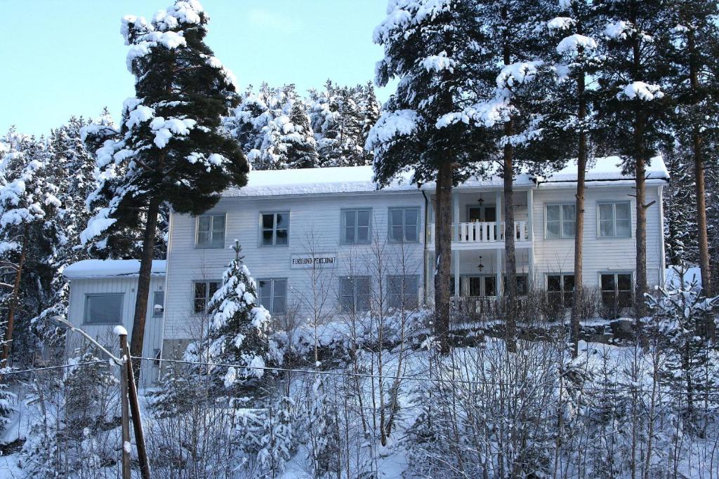 a white building with trees in the snow at Furulund Pensjonat in Ron