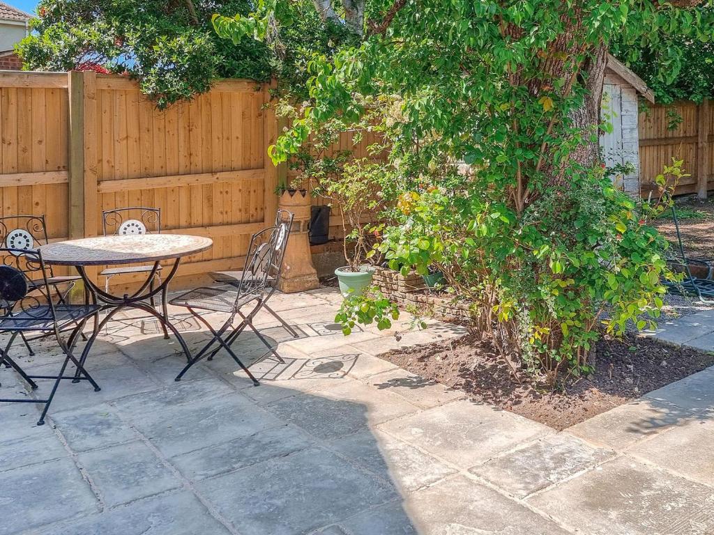 a patio with a table and chairs next to a fence at Pear Tree Cottage in Bath