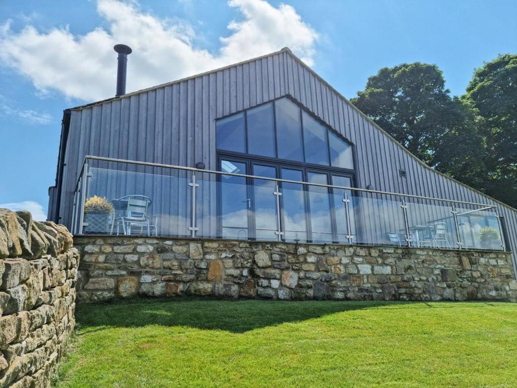 a house with glass windows on a stone wall at The Barn At Toft Hill Hall in High Etherley