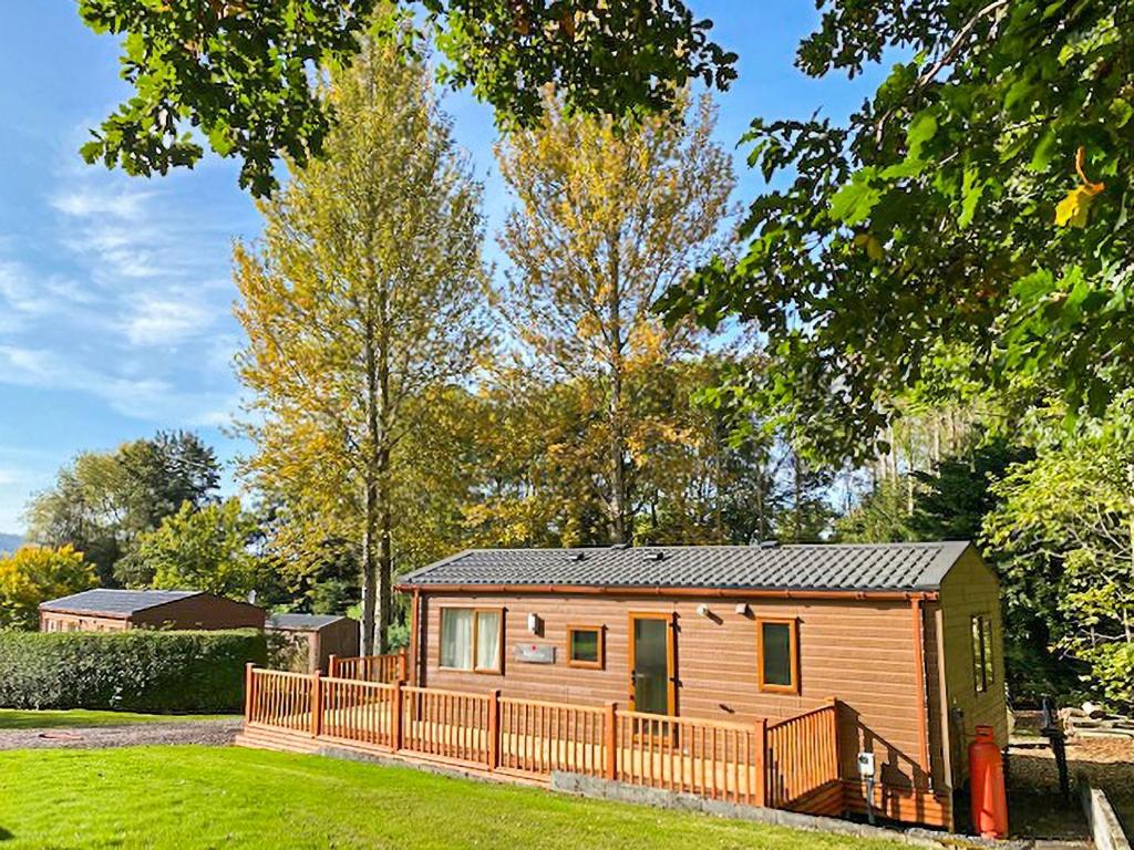 a wooden cabin in a yard with a fence at Avon Lodge in Hyssington