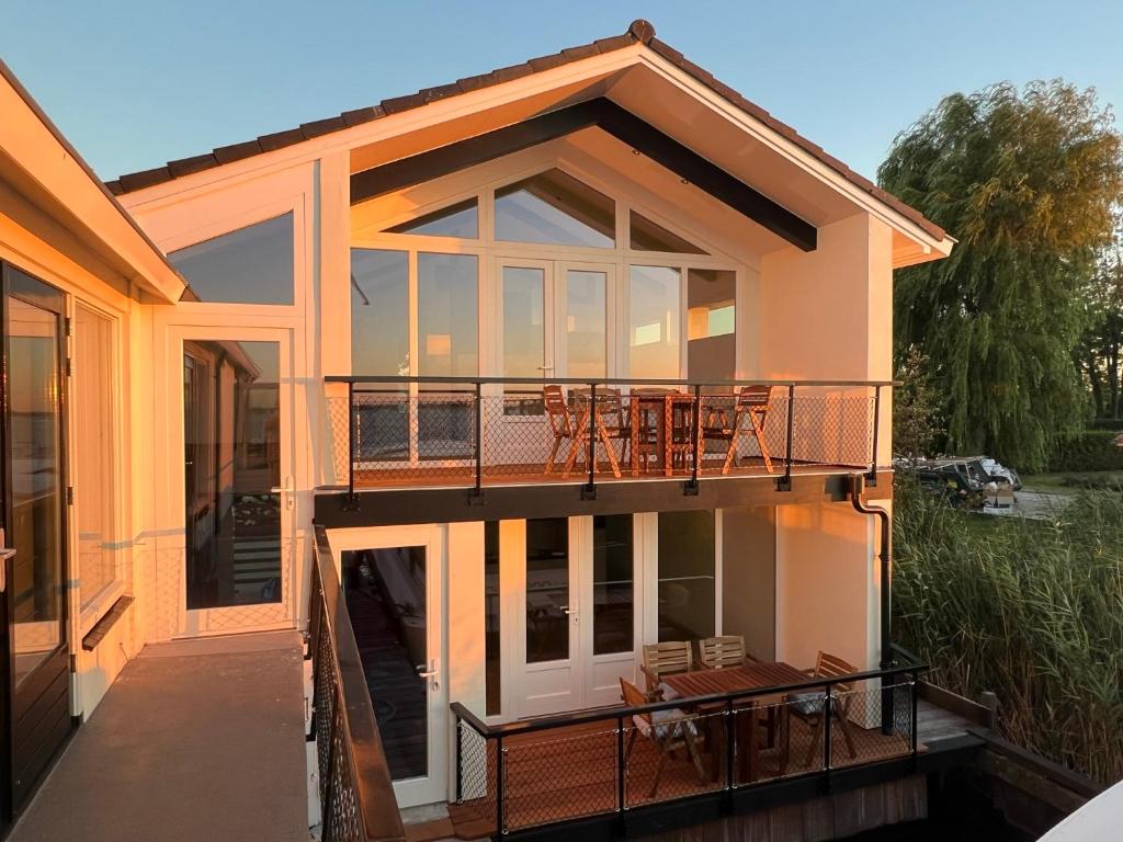 a house with a balcony and a deck at Plassenzicht Logies & Sloepverhuur in Loosdrecht