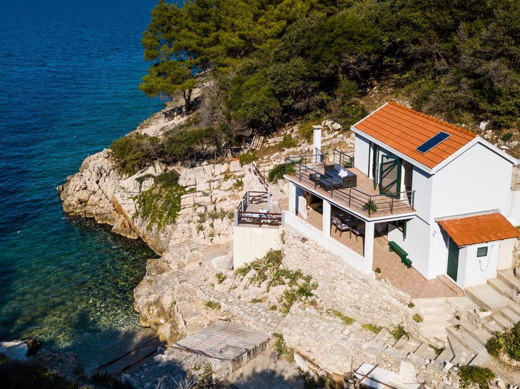 a house on a cliff next to the water at The Captain's Nook Spiliska in Blato