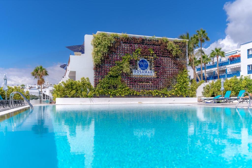 una piscina en un complejo con una pared de hiedra en Rosamar Apartamentos en Puerto del Carmen