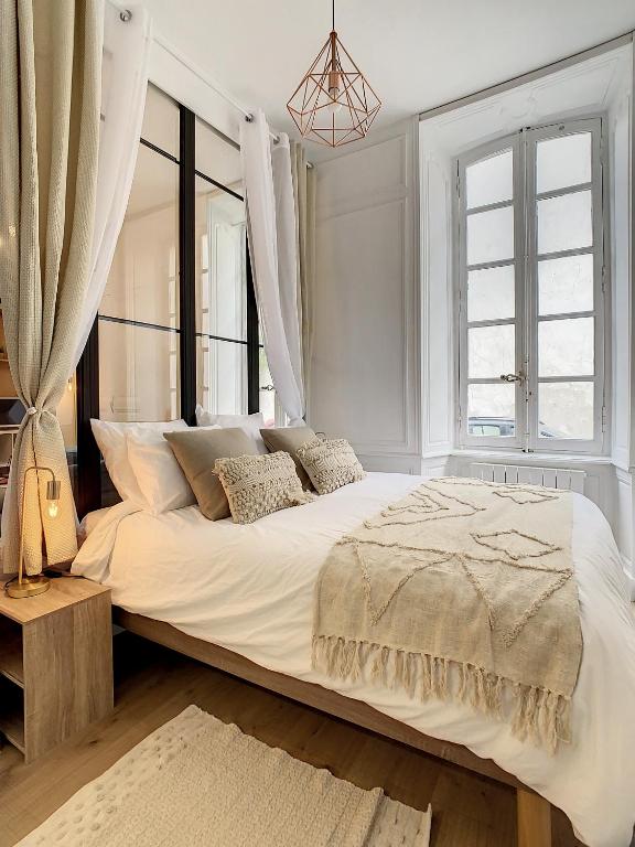 a white bedroom with a large bed and windows at Appartement de charme: La rochelle/vieux port in La Rochelle