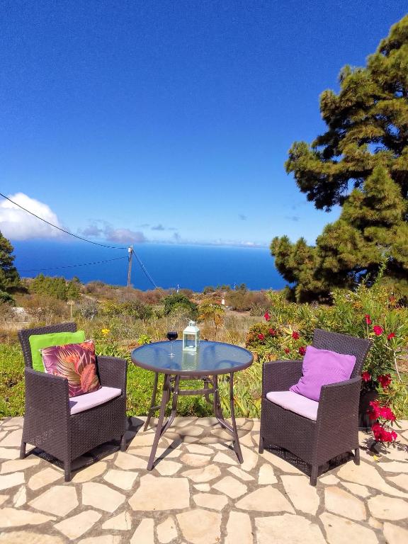 a patio with a table and two chairs and the ocean at Casa Flor azul in Las Tricias