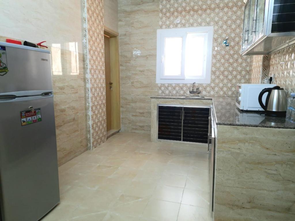 a kitchen with a refrigerator and a counter top at Grand Orchid Hotel Apartment in Duqm