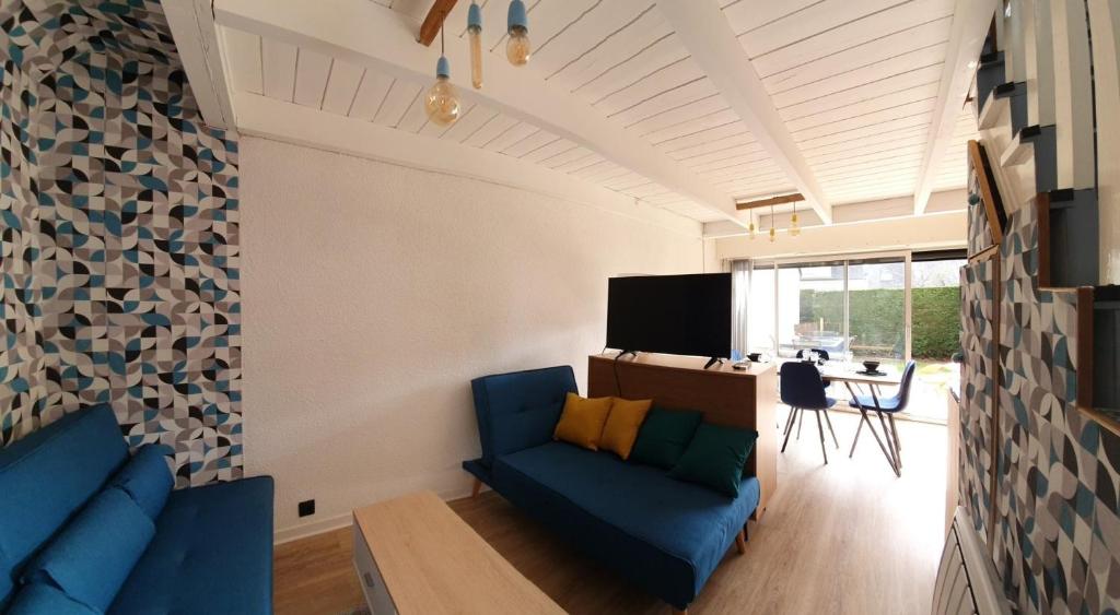 uma sala de estar com um sofá azul e uma mesa em Escapade marine a carnac Maison 4 personnes toute équipée, au calme entre plage et ville em Carnac