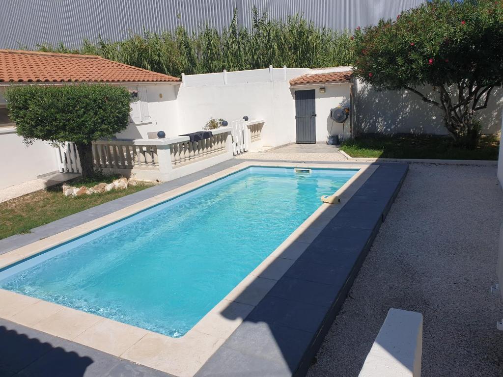 - une piscine d'eau bleue en face d'une maison dans l'établissement Adorable Romantique Maison d'hôte, piscine, wifi 4G, proche BEZIERS, à Cers