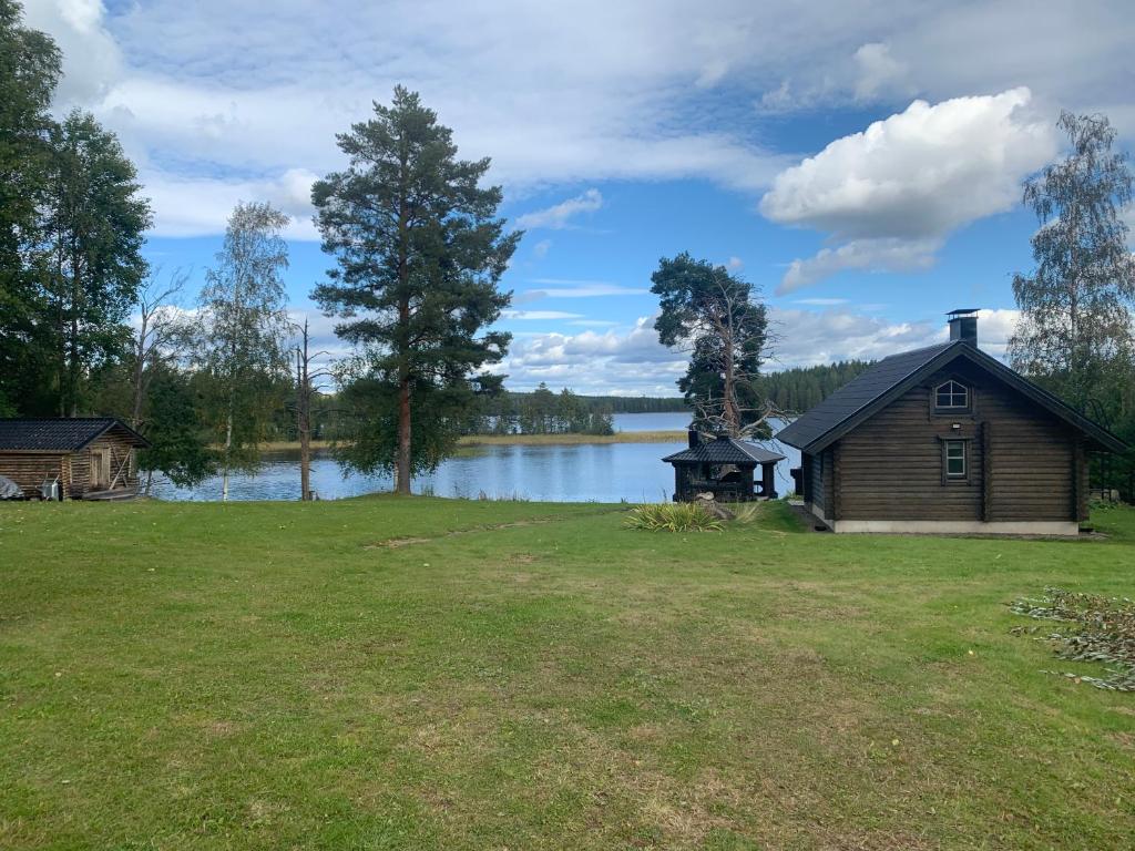 a house in a field next to a lake at Villa Konnekoski, pearl front of Etelä-Konnevesi National park in Rautalampi