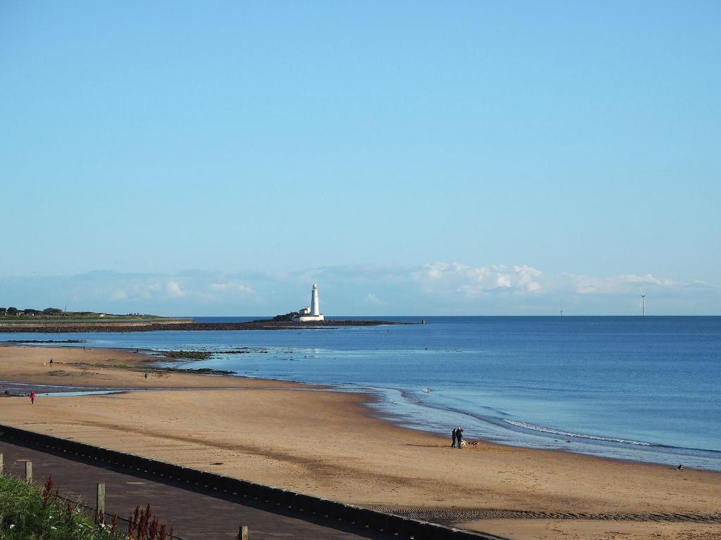 une plage avec un phare au loin dans l'établissement The Sands, à Whitley Bay