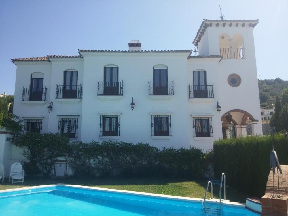 a large white building with a swimming pool in front of it at Rural Vega de Cazalla in Cazalla de la Sierra